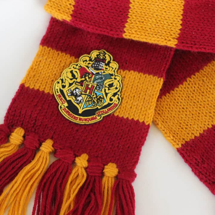 Harry Potter Knitted Scarf in Burgundy and Gold yarn colors with Hogwarts patch.