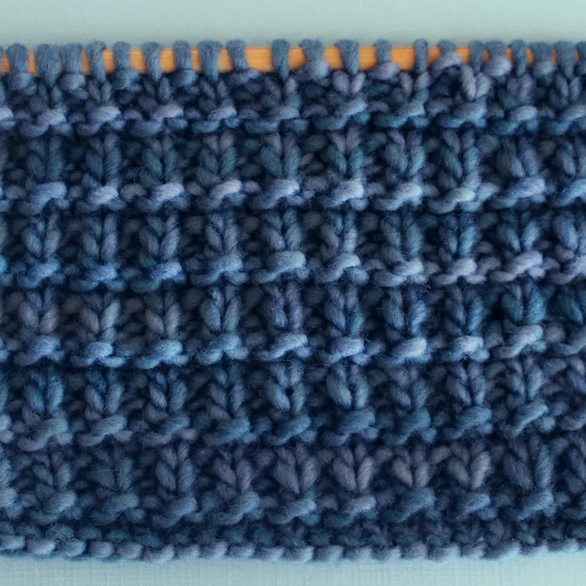 Hurdle Basket Weave Stitch Knitting Pattern in blue yarn color on knitting needle.