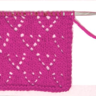 Mini Lace Heart Knit Stitch Pattern in pink yarn on knitting needle.