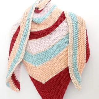Knitted Striped Shawl with horizontal stripes in burgandy, peach, light blue, pink, and white yarn colors.