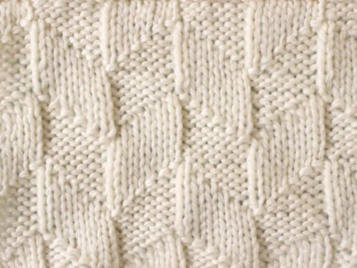 Parallelogram Knit Stitch Pattern texture in white yarn on knitting needle.