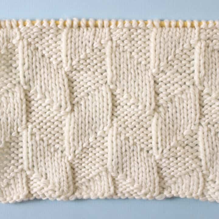Parallelogram Knit Stitch Pattern texture in white yarn on knitting needle.