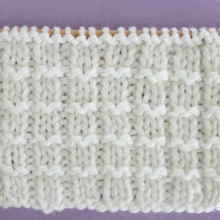 Pique Rib Knit Stitch Pattern in white yarn on knitting needle.