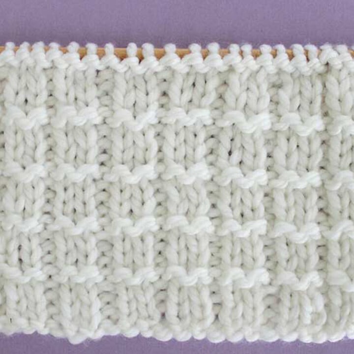 Pique Rib Knit Stitch Pattern in white yarn on knitting needle.