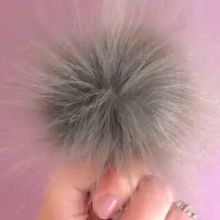 Pom Pom in Faux Fur Fabric in color grey held by hand.