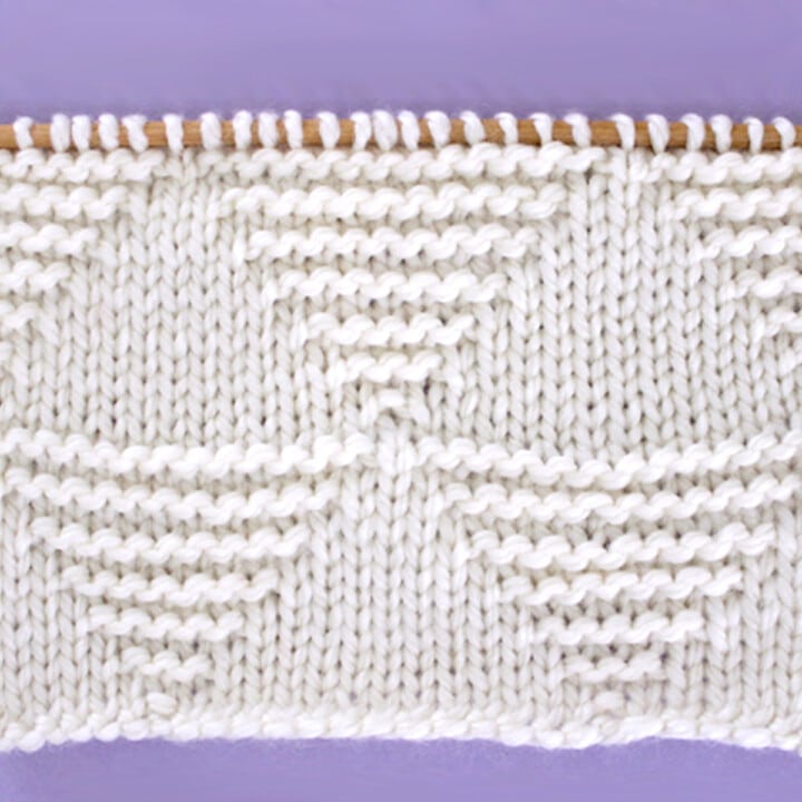 Knitted Stacked Triangle Stitch Pattern texture in white yarn on knitting needle.