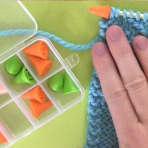 Needle Point Protector Stoppers on Knitting Needle with knitted swatch and hand.