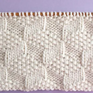 Tumbling Moss Knit Stitch Pattern in white yarn color on knitting needles.