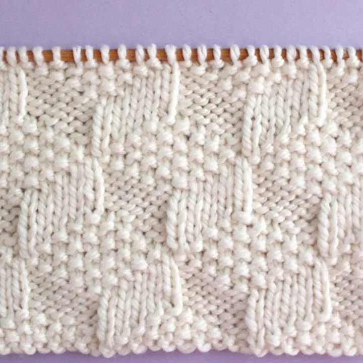 Tumbling Moss Knit Stitch Pattern in white yarn color on knitting needles.
