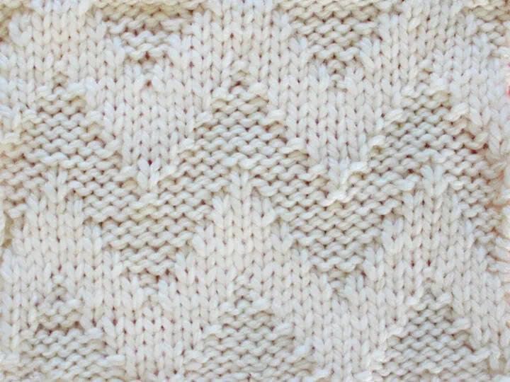 Knitted Wide Chevron Stitch Pattern in white yarn on knitting needle.