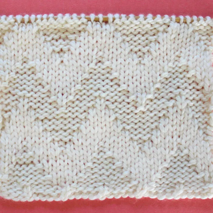 Knitted Wide Chevron Stitch Pattern in white yarn on knitting needle.