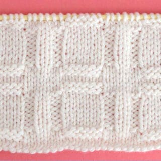 Knitted Window Stitch Pattern in white yarn on knitting needle.