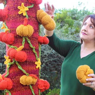 Knitted Pumpkin Tree being crafted by woman while yarnbombing.