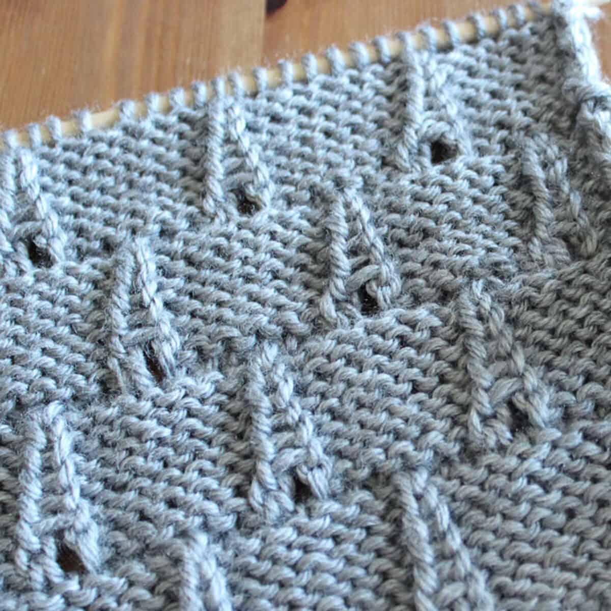 Eiffel Tower Eyelet Stitch Knitting Pattern texture in gray color yarn on knitting needle.