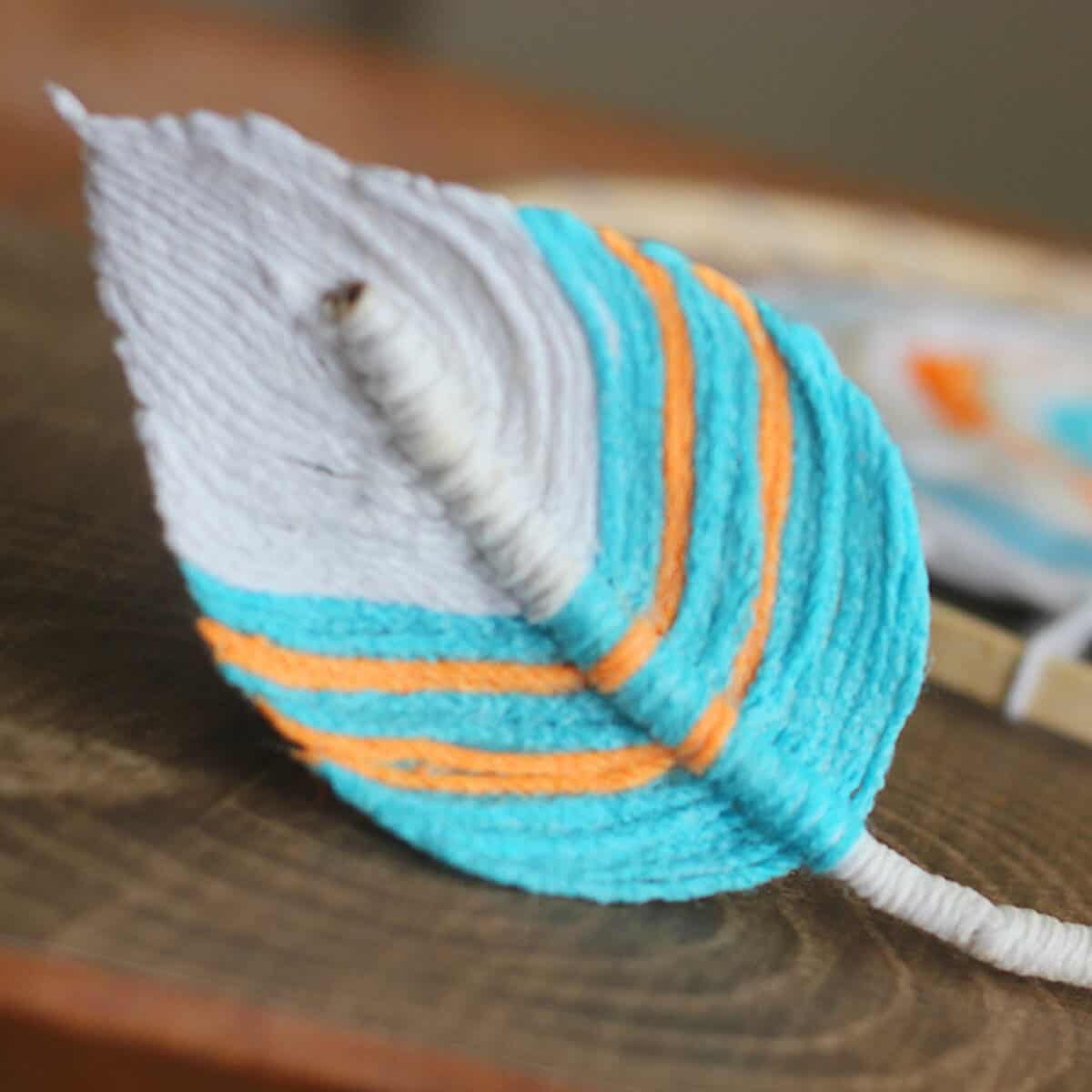 Fiber Feather created with yarn in blue, orange, and white colors.