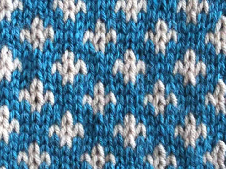 Fleur De Lys Stitch Knitting Pattern texture in blue and white colors of yarn.