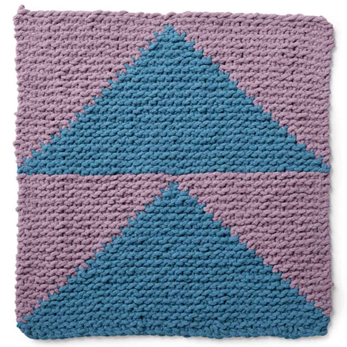Knitted Square in the Flying Geese Design with shades of blue and purple yarn colors.