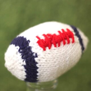 Knitted Football softie toy in white, blue, and red yarn colors.