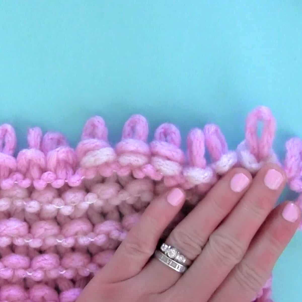Loop yarn in pink color with woman's hand.