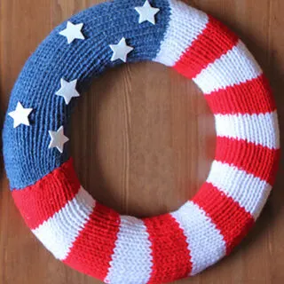 Knitted wreath in american flag design with red, white, and blue yarn colors.