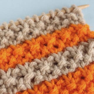 Right side of knitted swatch in tan and orange color yarn.