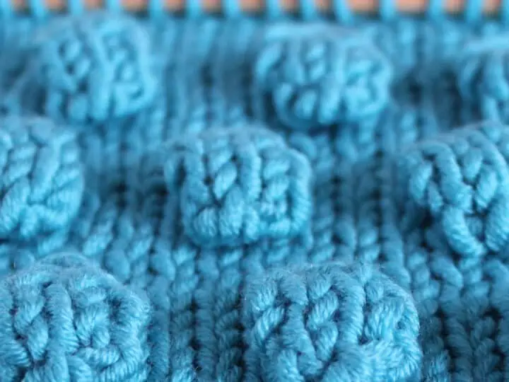 Bobbles in Stockinette Stitch on knitting needle in blue color yarn.