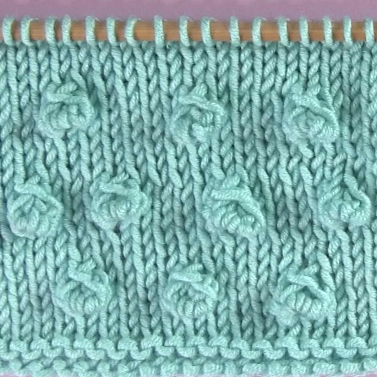 Small sized Bobbles in Stockinette Stitch on knitting needle in light blue color yarn.