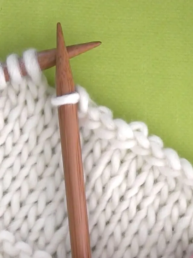 Cast off knitting stitches with needles and white color yarn.