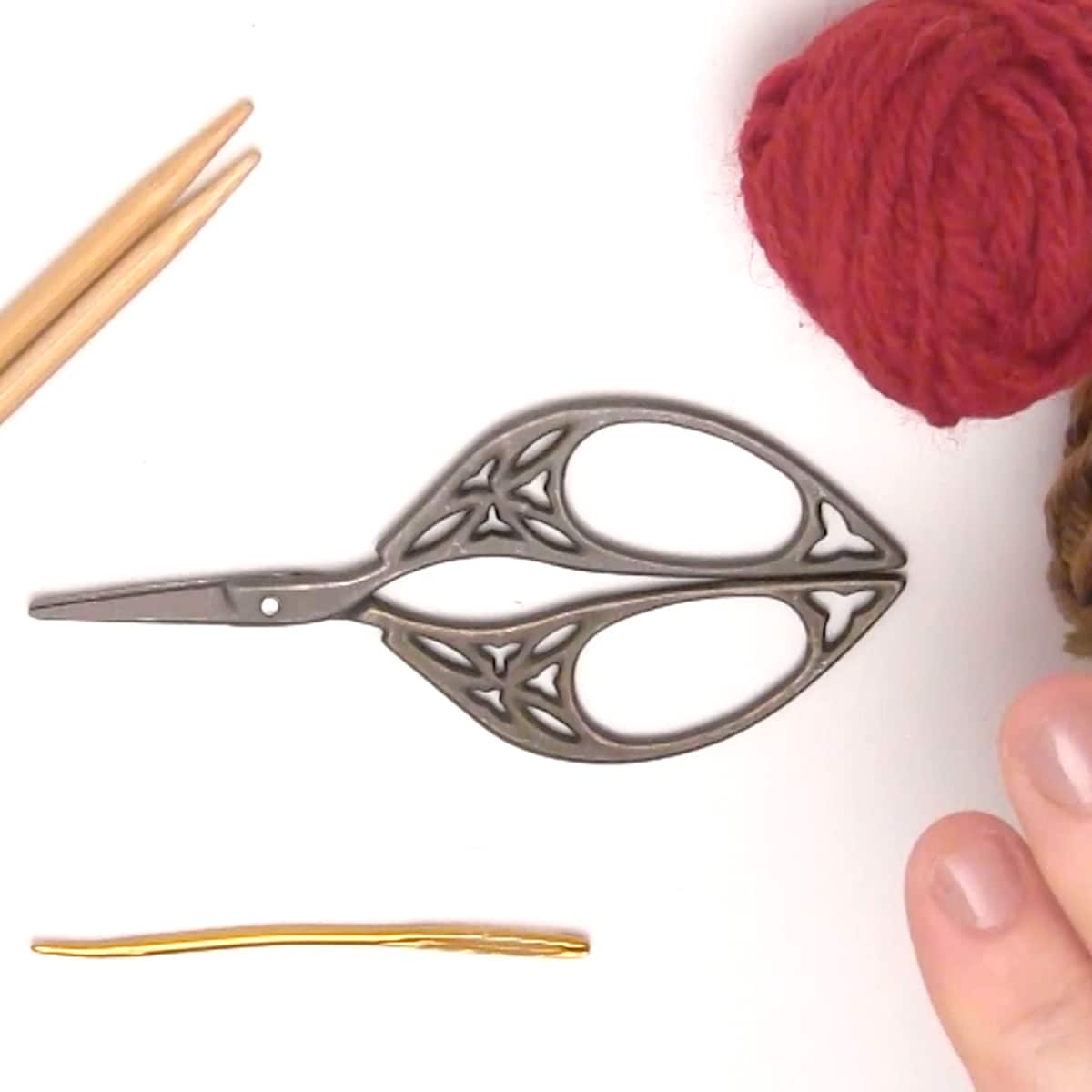 Knitting materials for acorns with yarn, needles, tapestry needle, and scissors.