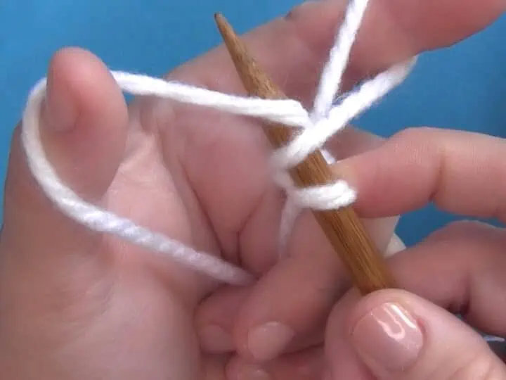 Hands demonstrating How to Long Tail Cast On Purlwise with yarn and knitting needles.