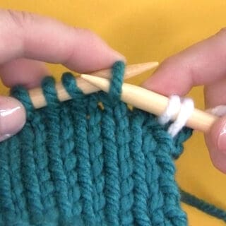 Demonstration of Slip Stitch technique with yarn and knitting needles.