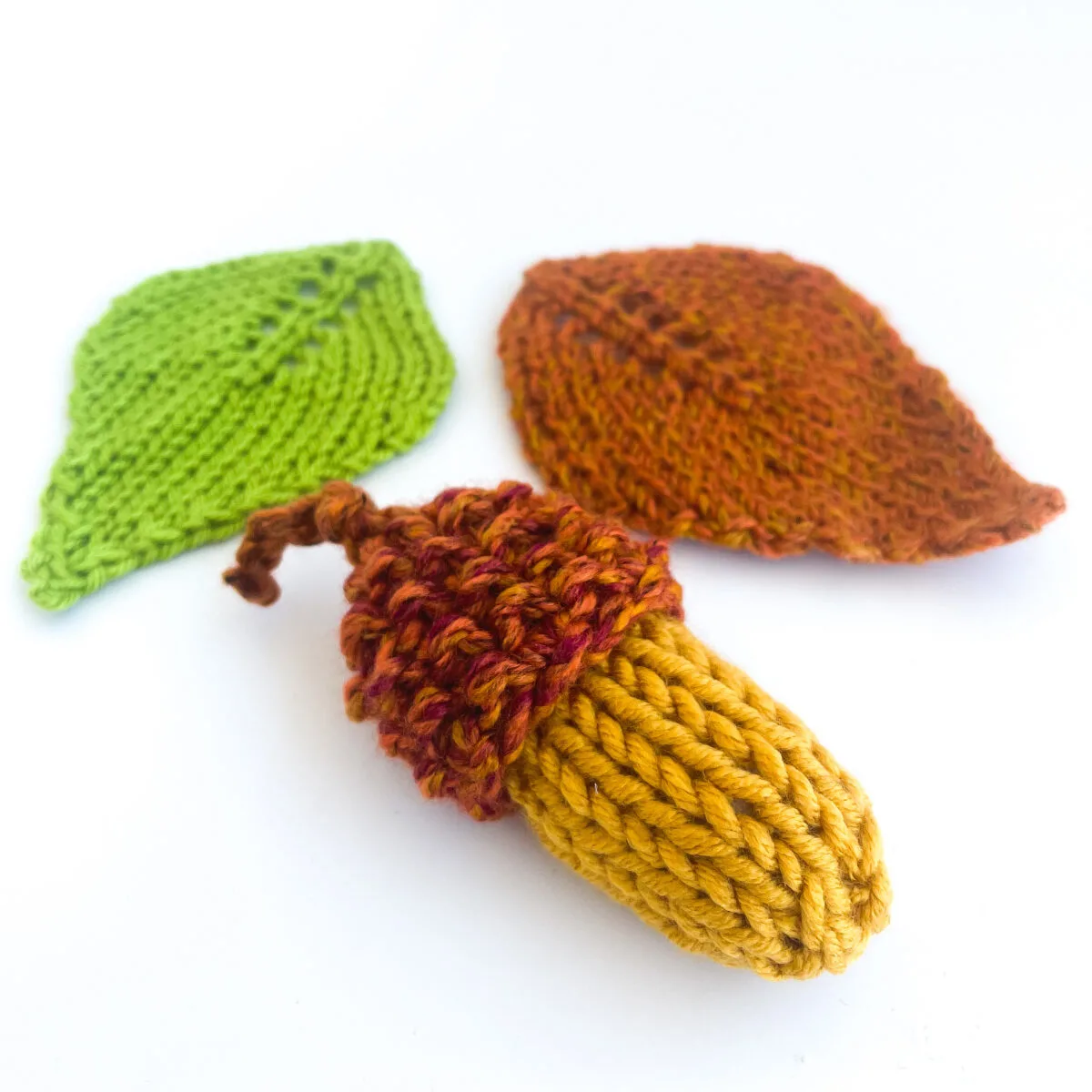 Knitted acorn with two knitted leaves.