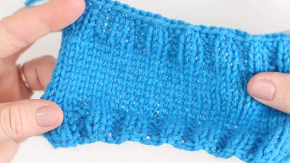 Knitted body swatch of coffee cozy in blue color yarn.