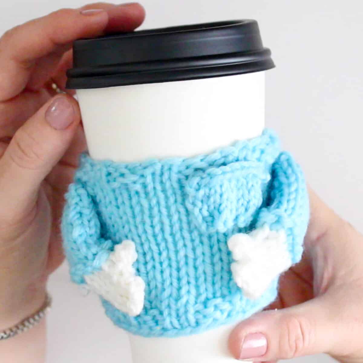Finished knitted mug cozy in light blue yarn .