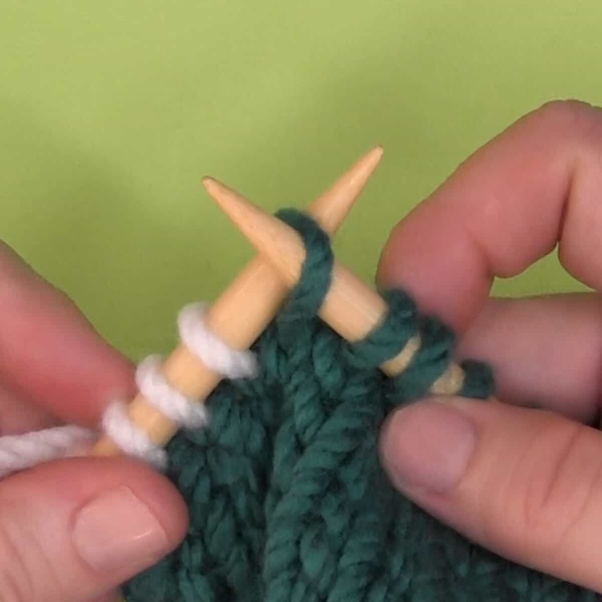 Left-handed demonstration of inserting needle knitwise into the back loop.
