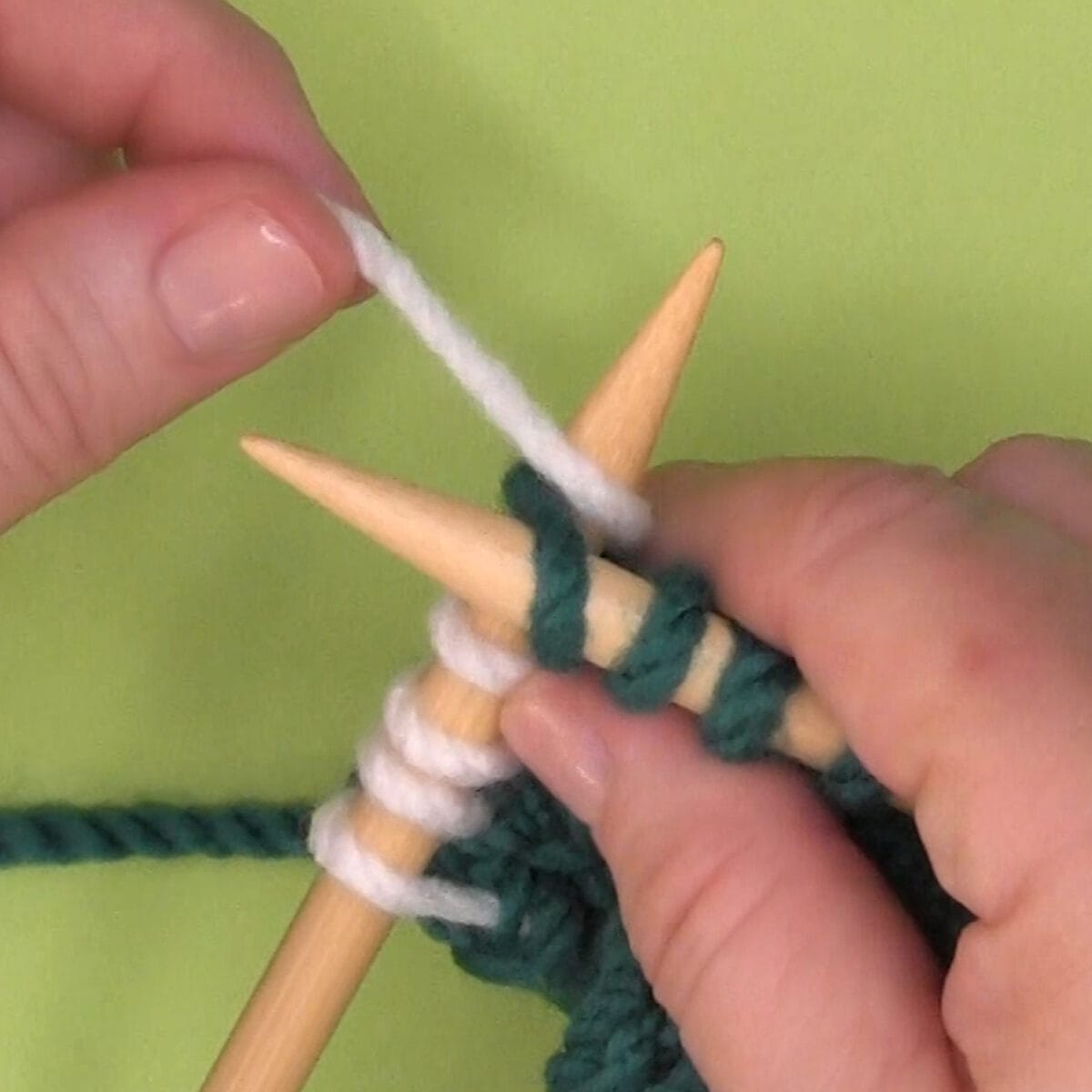Left-handed demonstration of wrapping yarn counterclockwise around needle.