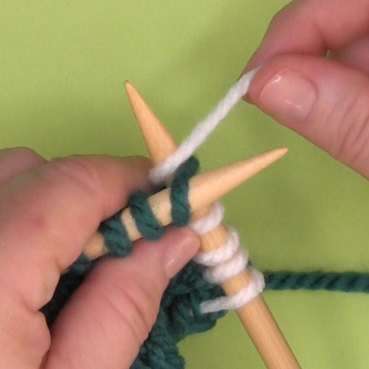 Right-handed demonstration of wrapping yarn counterclockwise around needle.