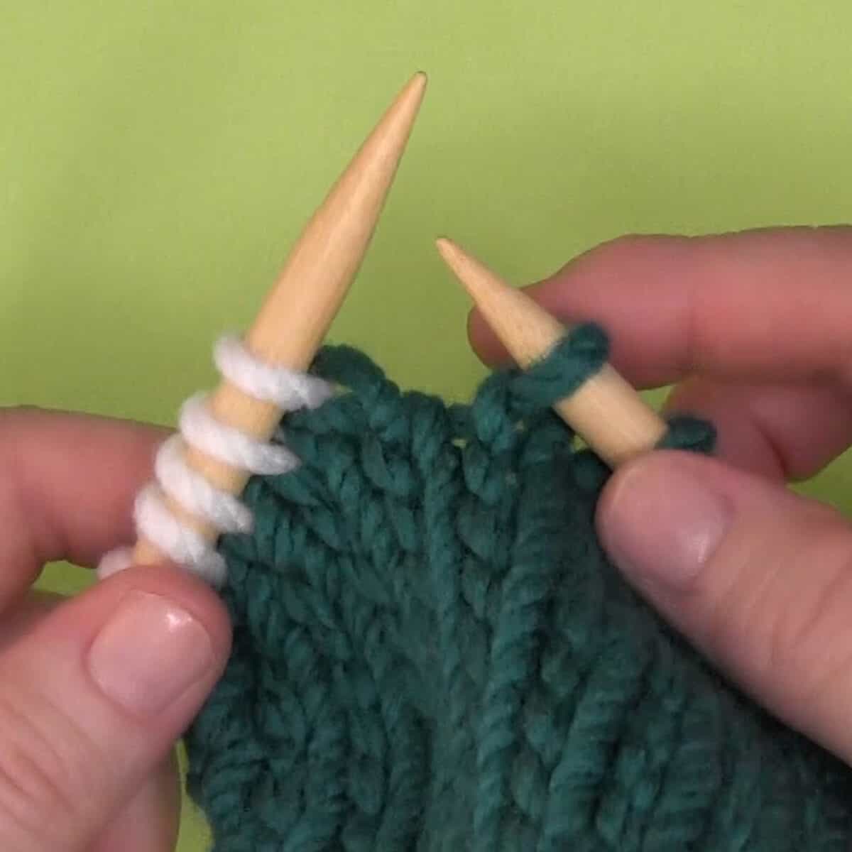 Left-handed demonstration of a finished twisted knit stitch.