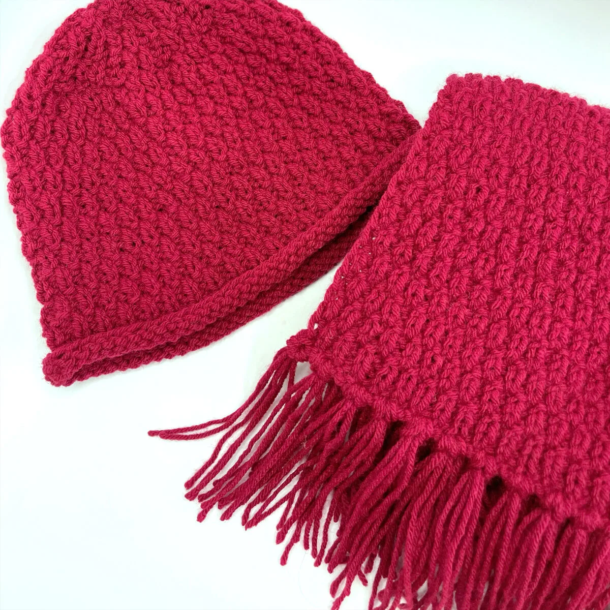 Knitted hat and scarf in burgandy red colored yarn.