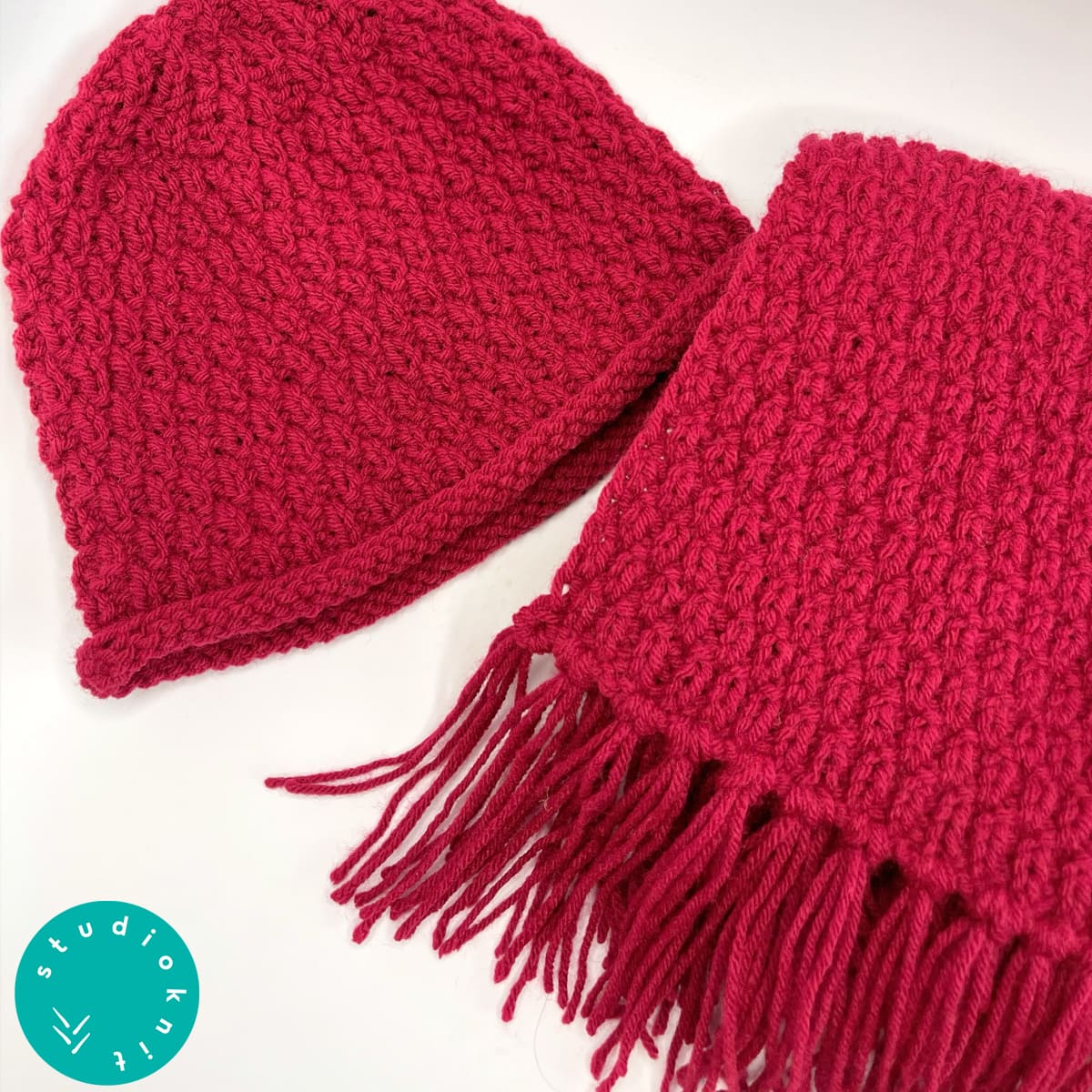 Knitted hat and scarf in burgundy red colored yarn.