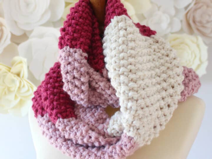 Seed Stitch Infinity Scarf Knitted with red, pink, and white yarn modeled on mannequin.