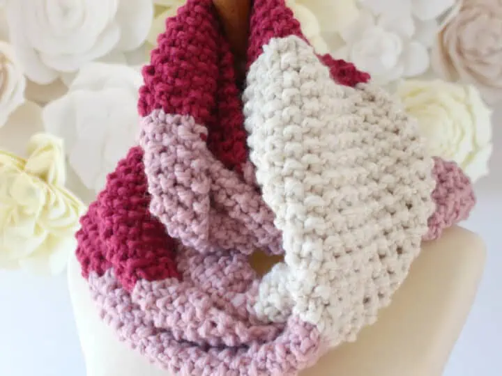 Seed Stitch Infinity Scarf Knitted with red, pink, and white yarn modeled on mannequin.