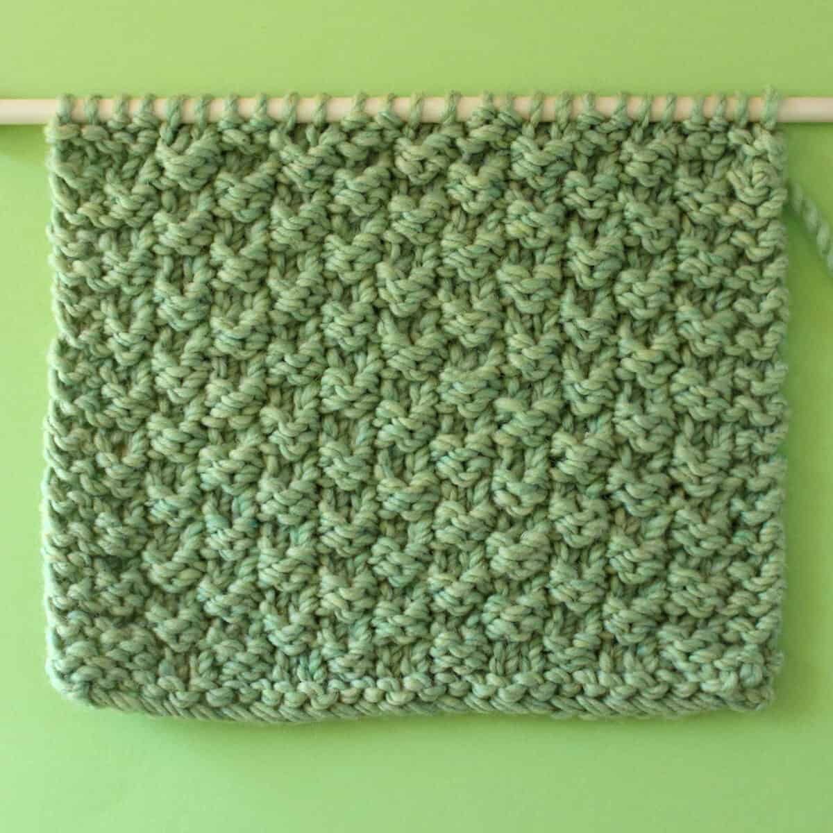 Double Moss Stitch texture on knitting needle in green color yarn.