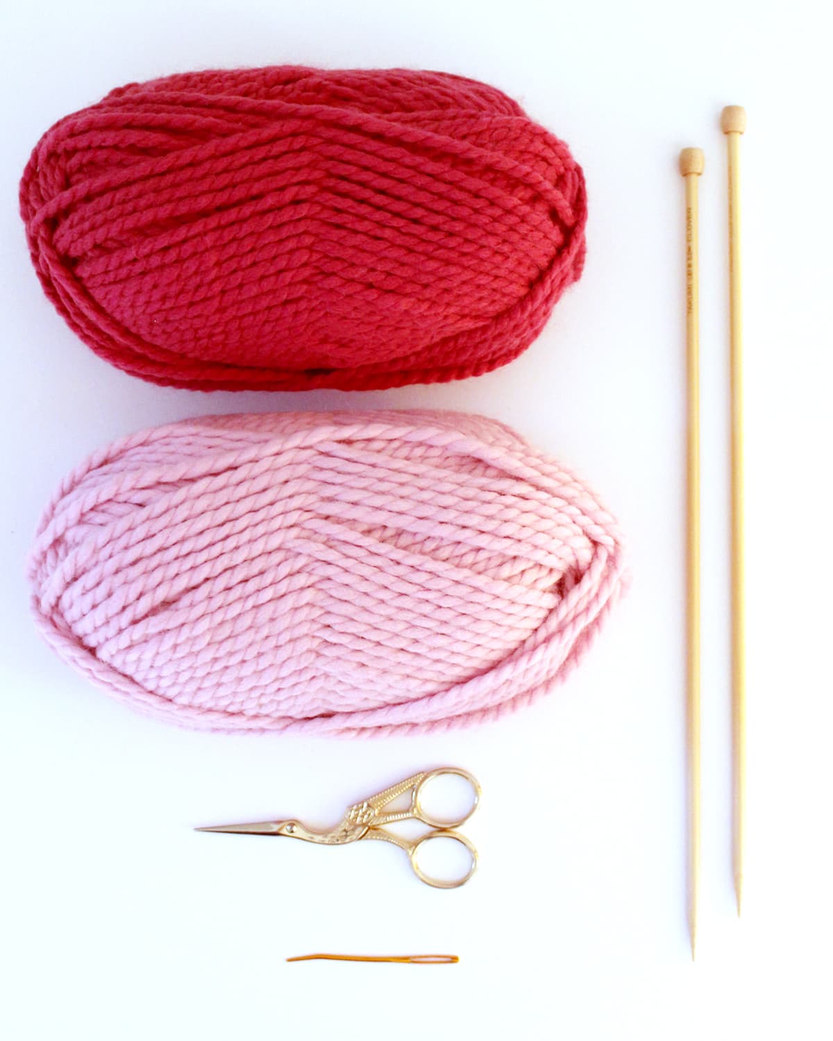Knitting supplies of yarn, needles, scissors, and tapestry needle.