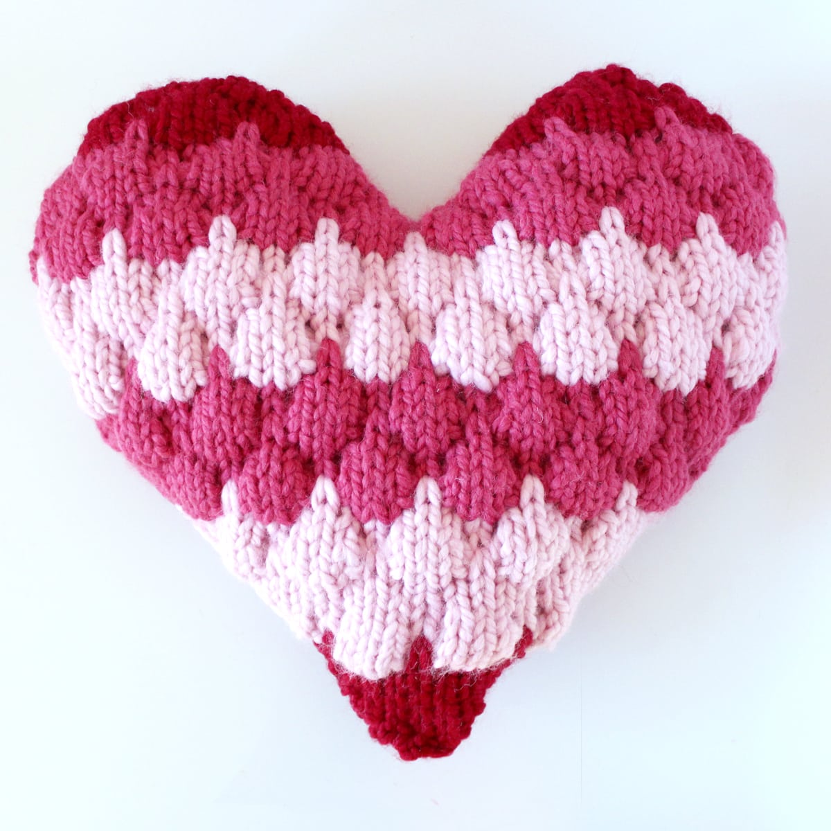 Bubble Stitch Heart Pillow in red and pink yarn colors.