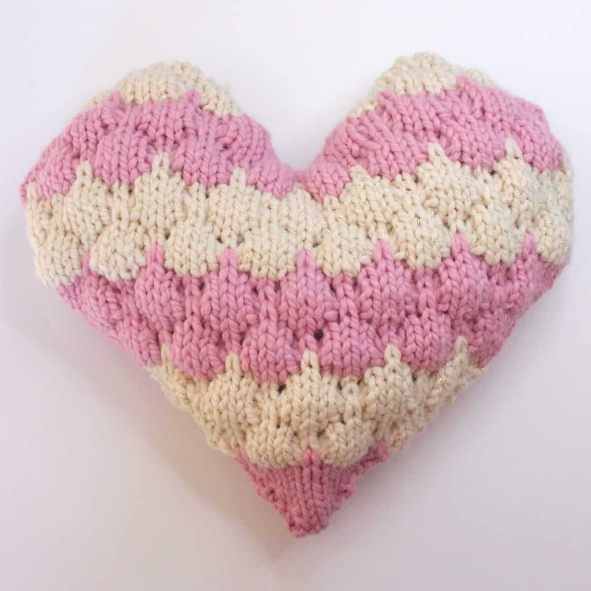 Heart Shaped Bubble Stitch knitted pillow in cream and pink yarn colors.