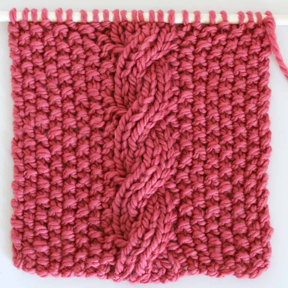 Reversible Cable Stitch Ribbles on Seed Stitch Background in pink color yarn.