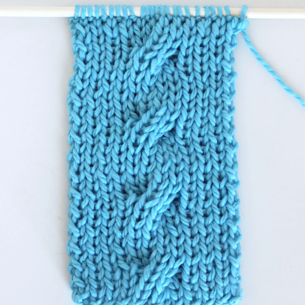 Reversible Cable Stitch Ribbles on 1x1 Rib Stitch Background in blue color yarn.
