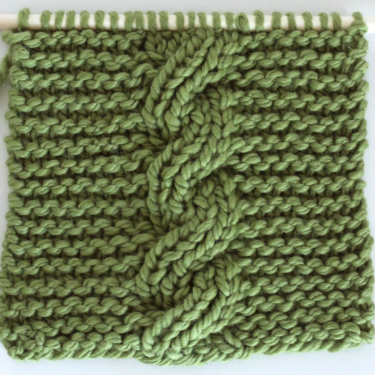 Reversible Cable Stitch Ribbles on Garter Stitch Background in green color yarn.