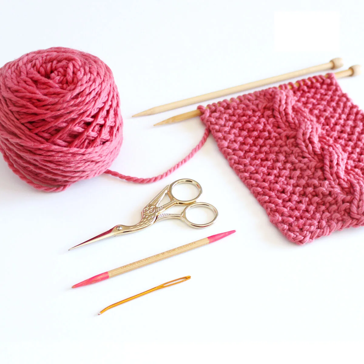 Knitting supplies with Cable Ribbles, yarn, knitting needles, cable needle, tapestry needle, and scissors.